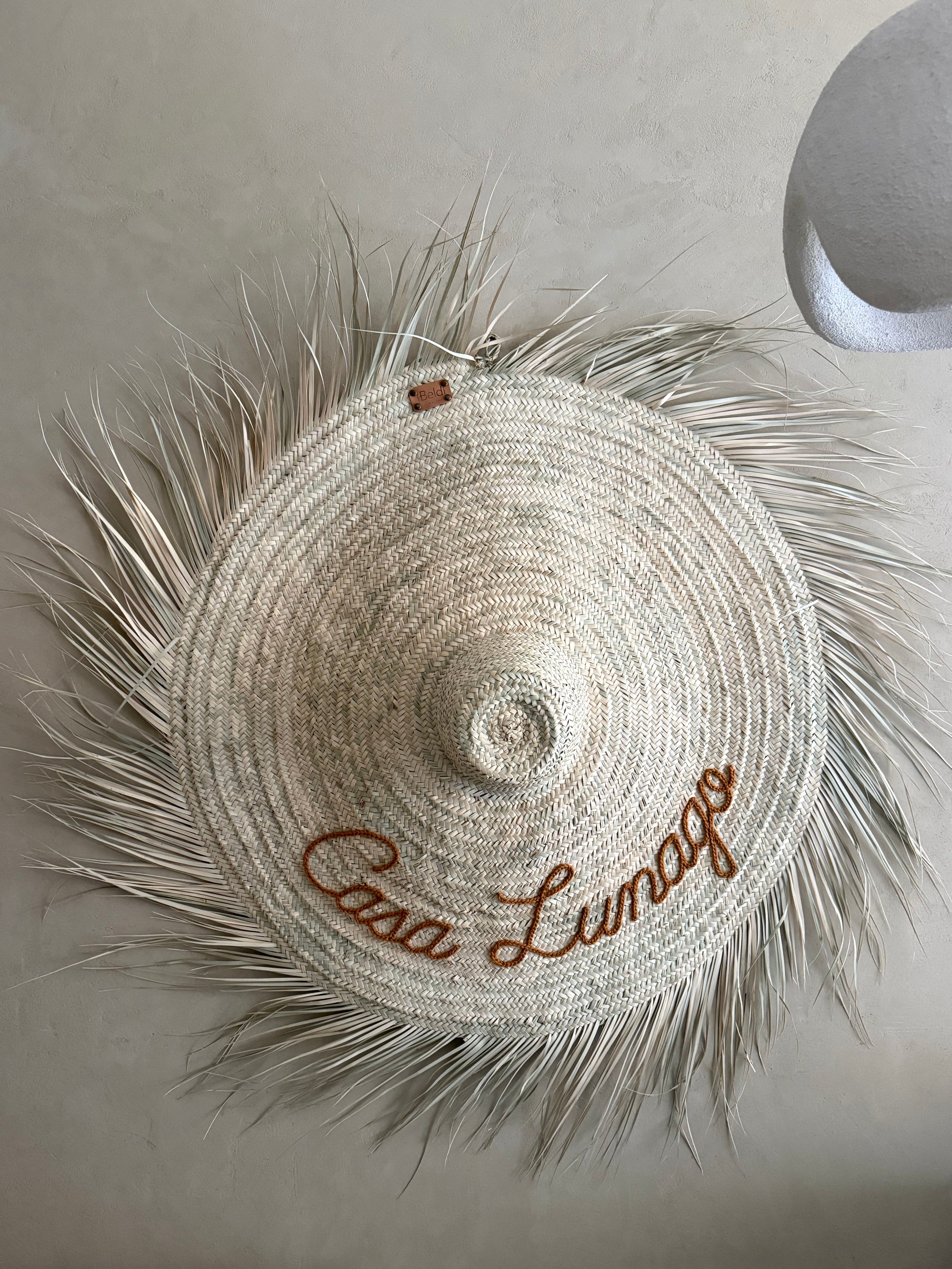 Détail de la broderie personnalisée sur chapeau en paille — nom de maison brodé main