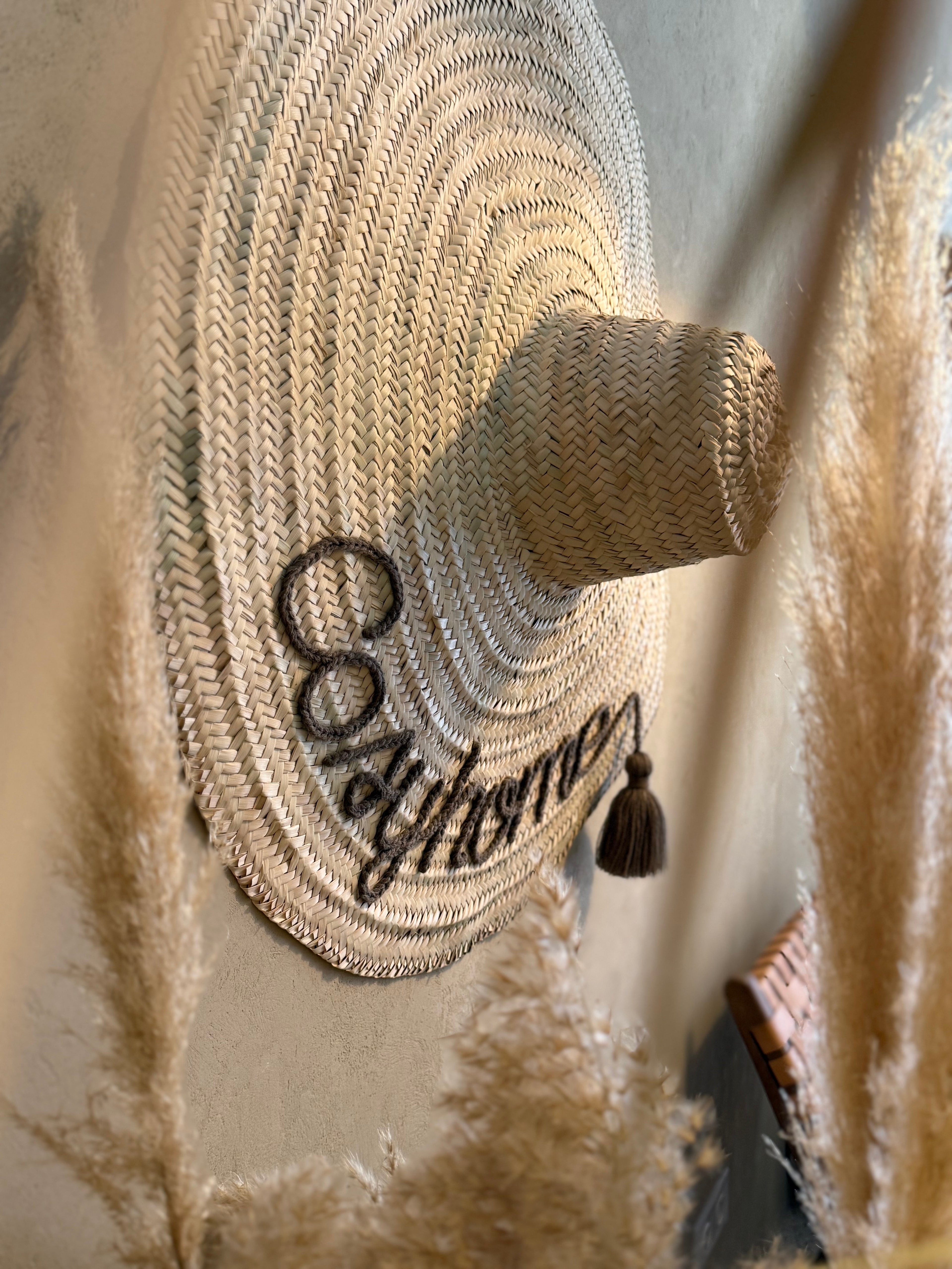 Personalized embroidered straw hat in a living room — bohemian wall decor